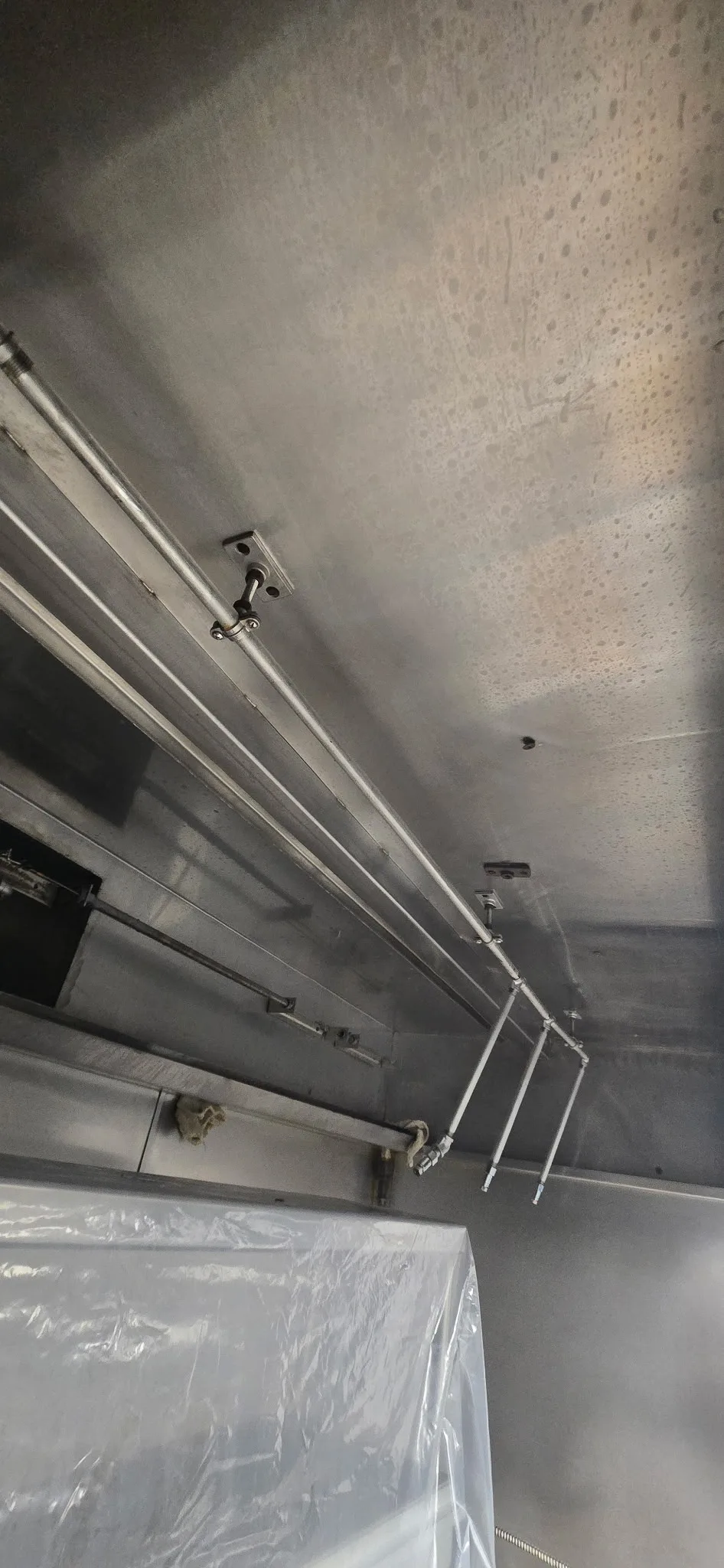 Hood interior after cleaning — wide angle view showing clean stainless ceiling and suppression lines fully restored