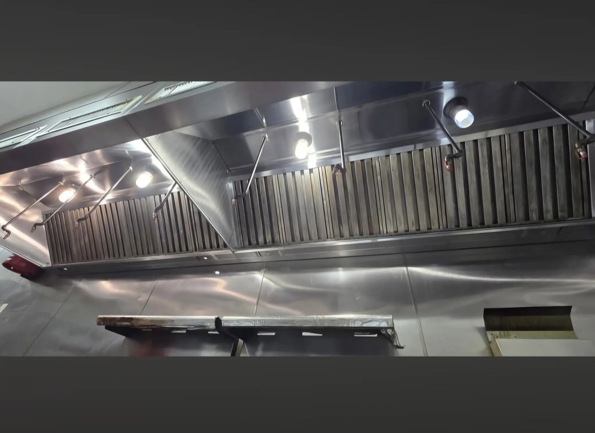 Wide commercial hood after cleaning showing clean filters and stainless interior