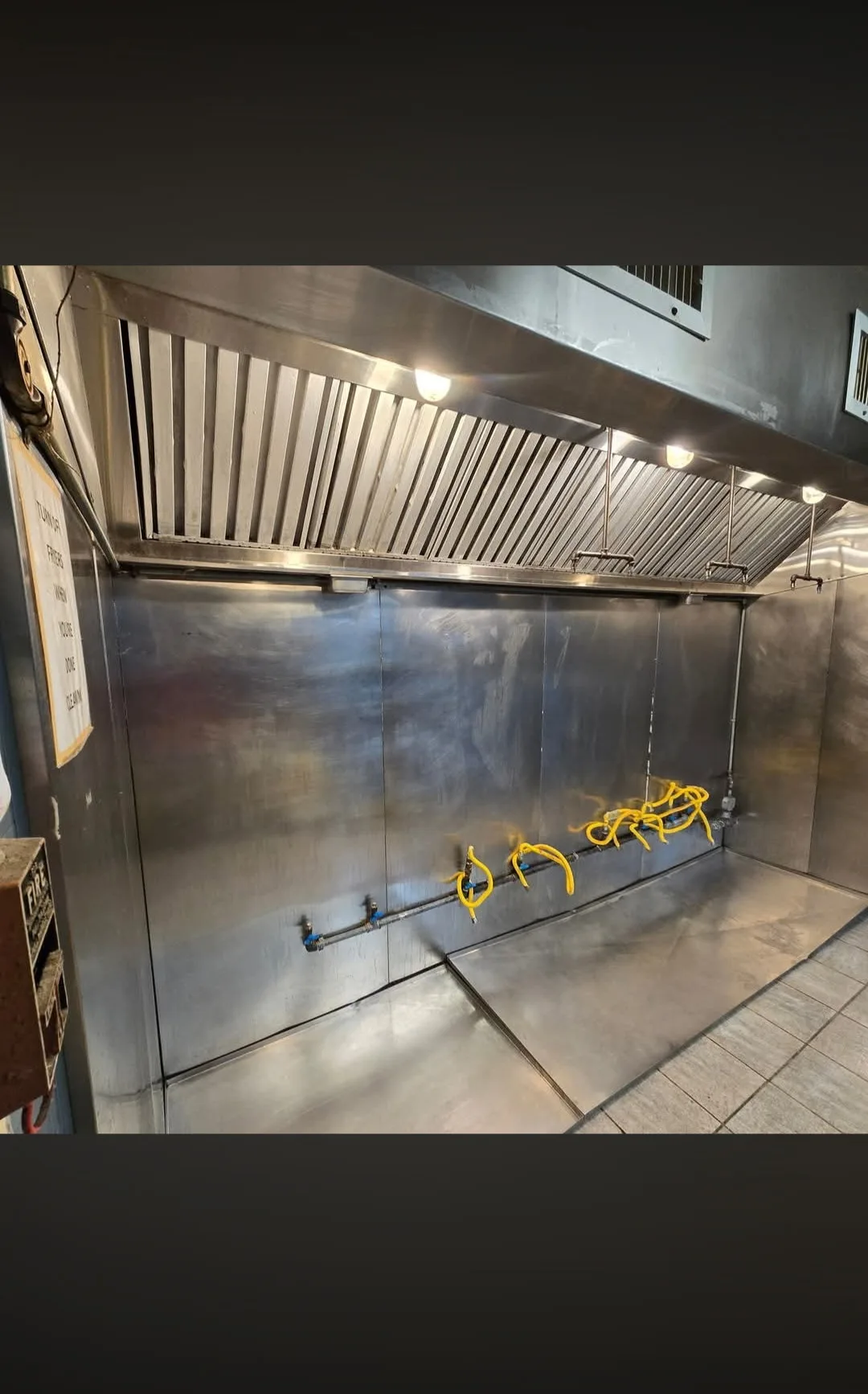 Commercial kitchen fryer area after cleaning with clean hood filters and equipment
