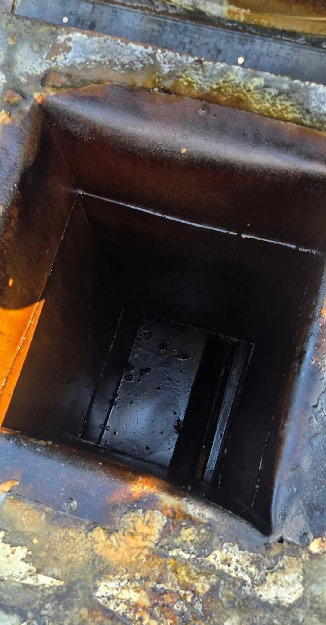 Commercial hood duct interior before cleaning showing heavy grease coating on all surfaces