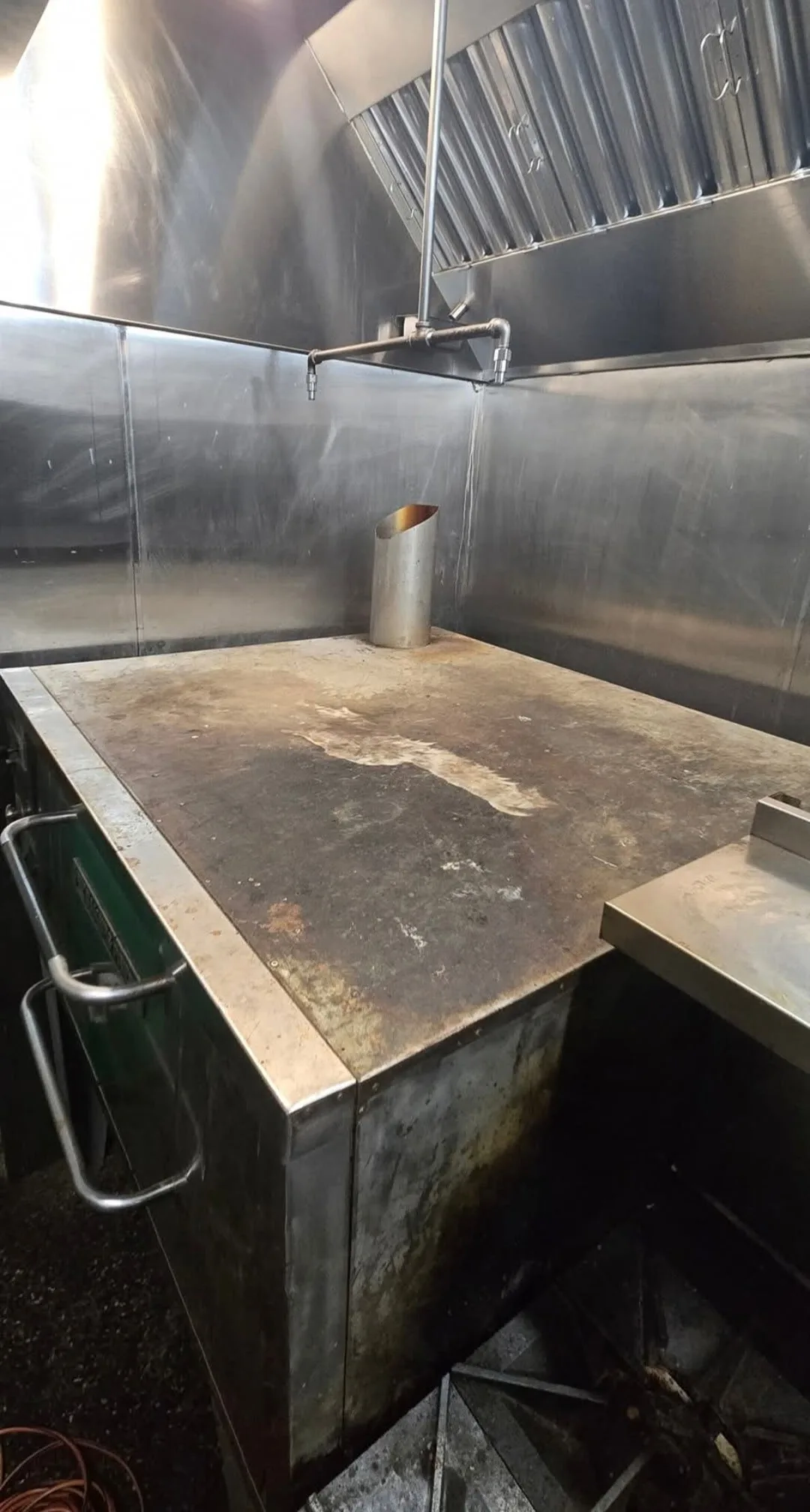 Wide shot of commercial kitchen equipment before cleaning showing grease and carbon accumulation across multiple units