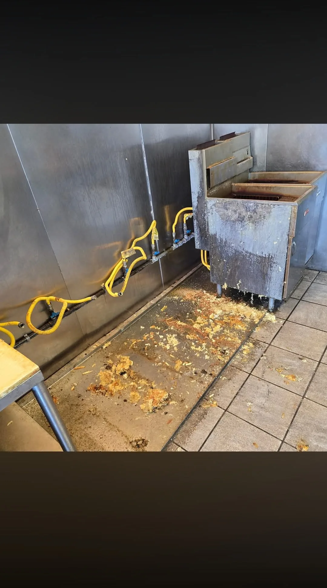 Commercial kitchen fryer area before cleaning with soiled equipment and floor