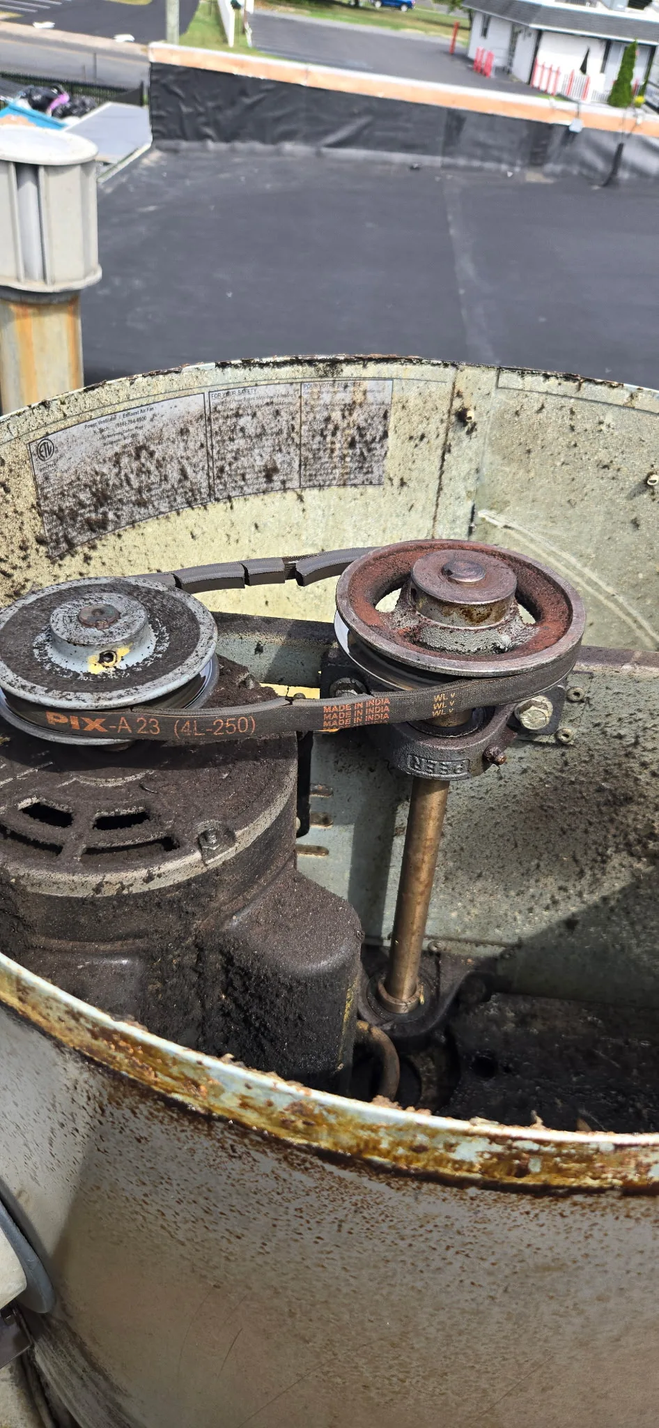 Drive belt and pulley system inside a commercial rooftop exhaust fan housing